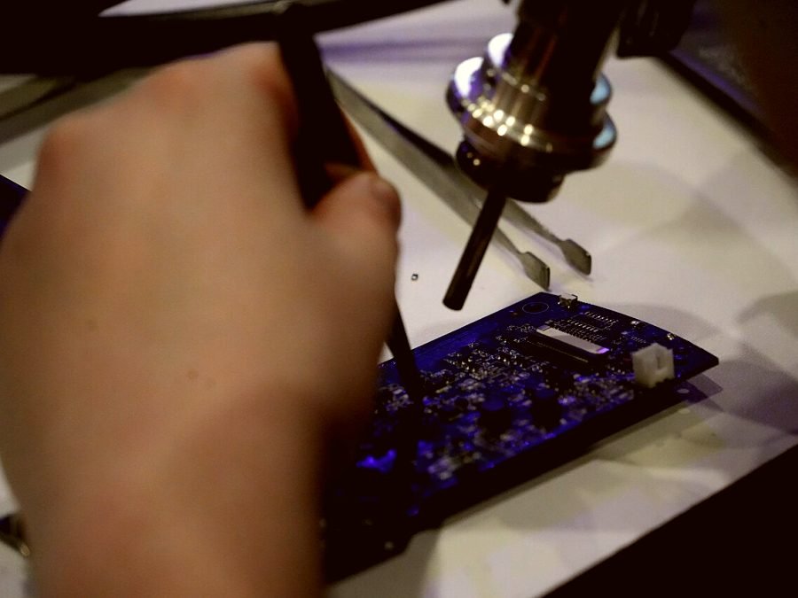 A technician soldering a component onto an appliance control board
