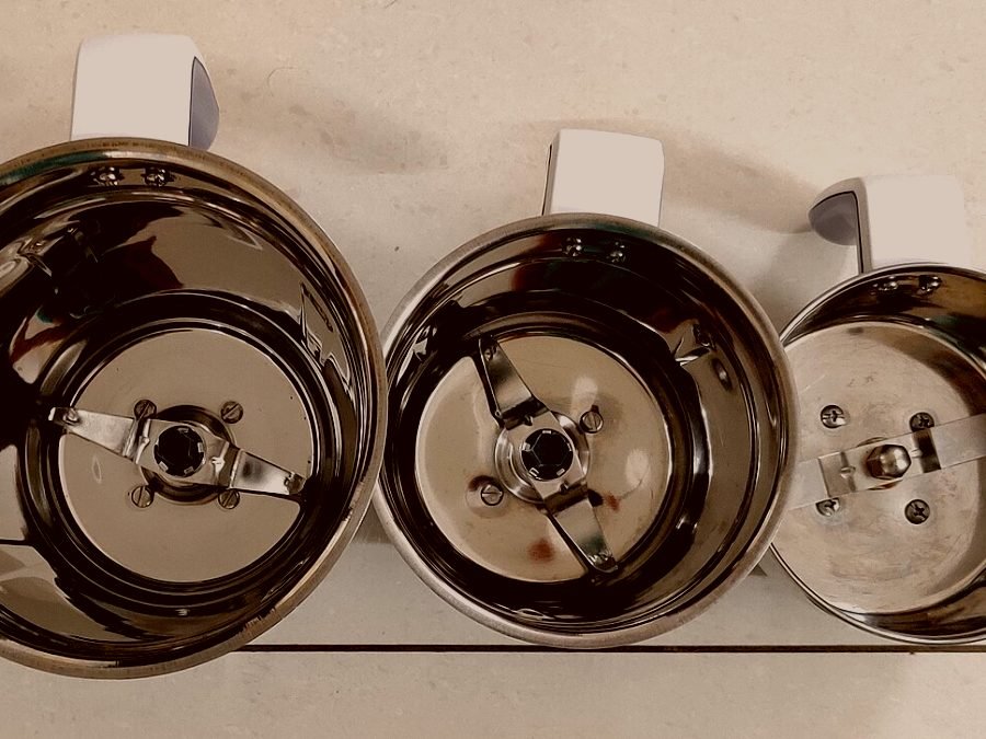 Three stainless mixer grinder jars with their blade assemblies removed for cleaning