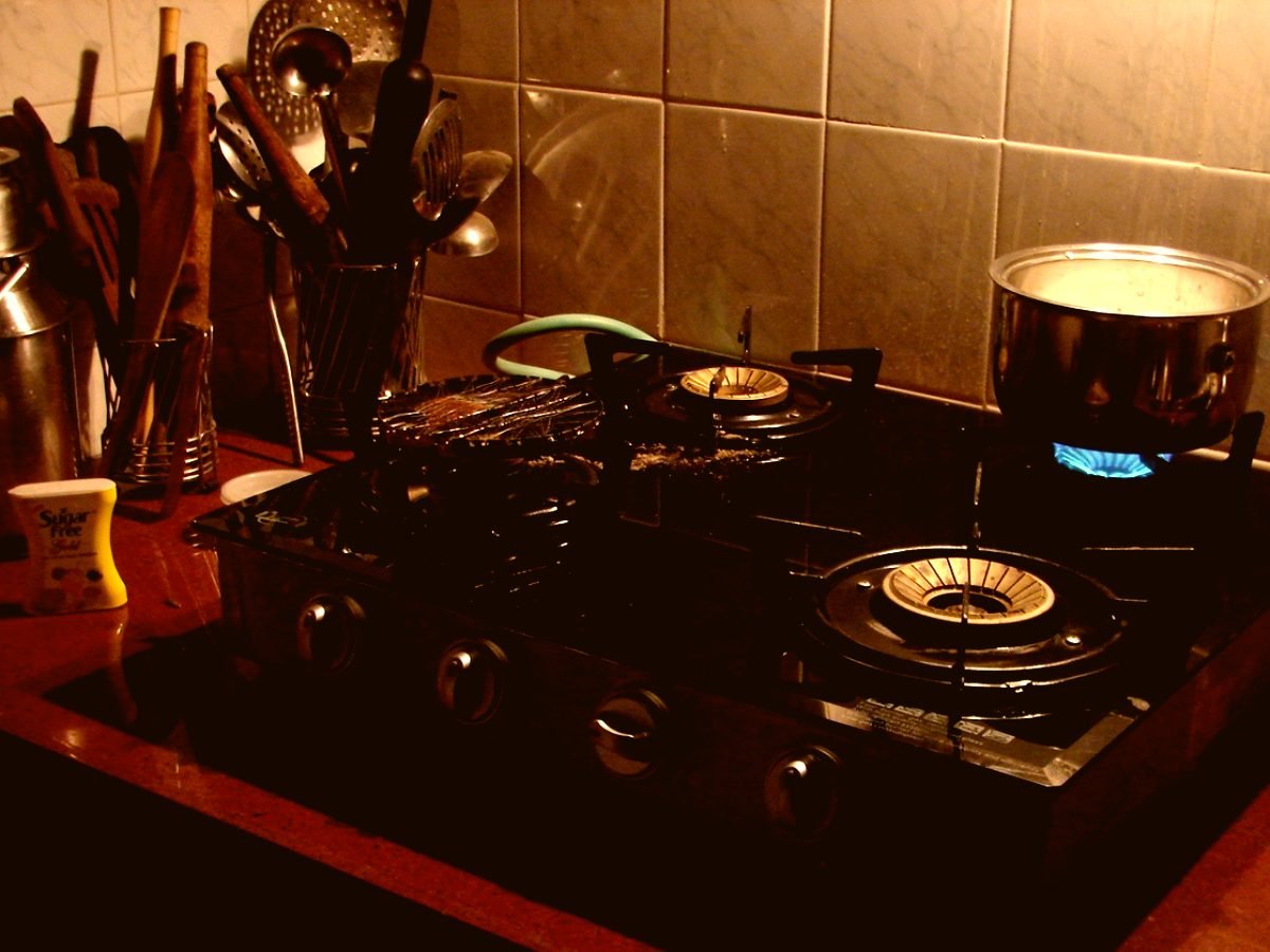 A Chennai home kitchen lit warm at night, with brass vessels and a gas hob